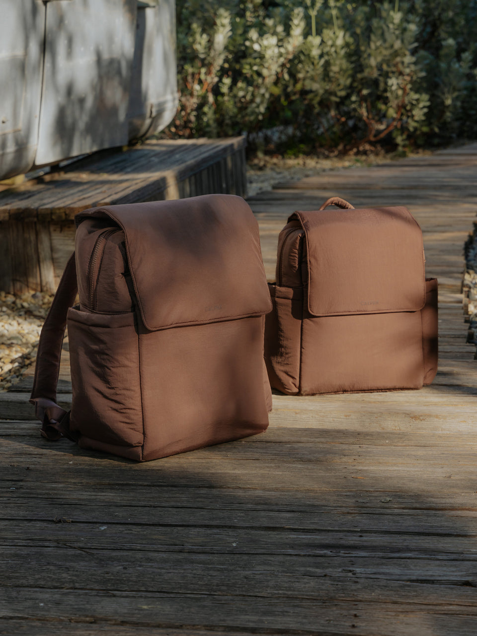CALPAK Diaper Backpack and  Mini Diaper Backpack in brown Hazelnut in a nature background; BPC2402-HAZELNUT
