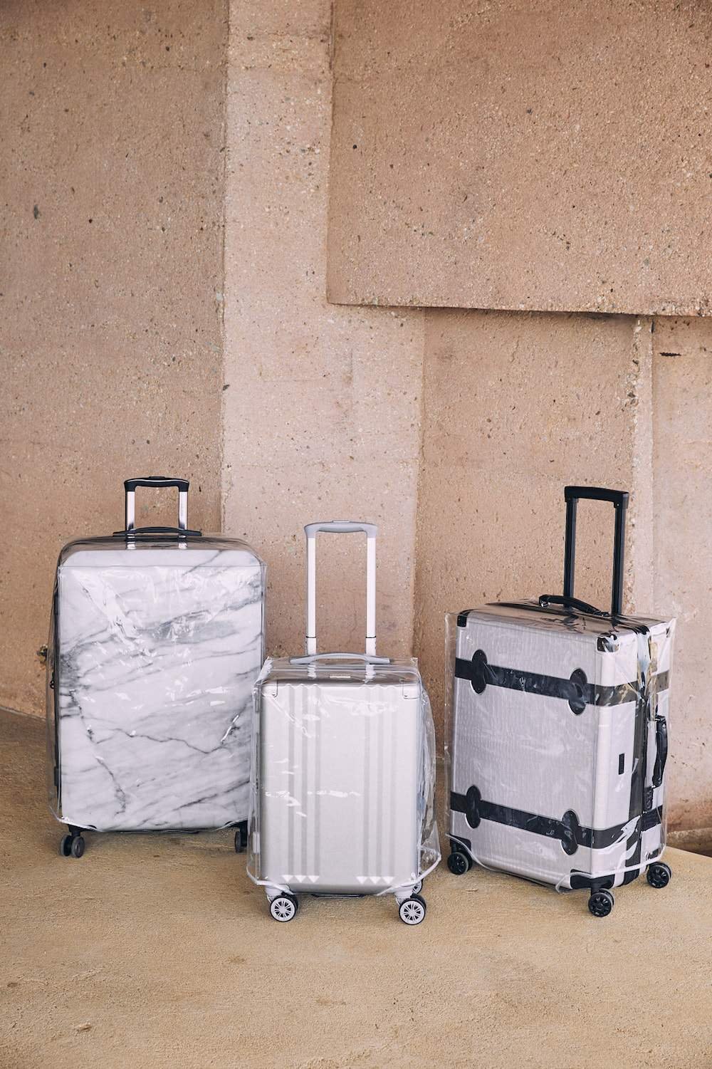 hardside carry on, medium suitcase and large luggage packed in clear plastic luggage cover
