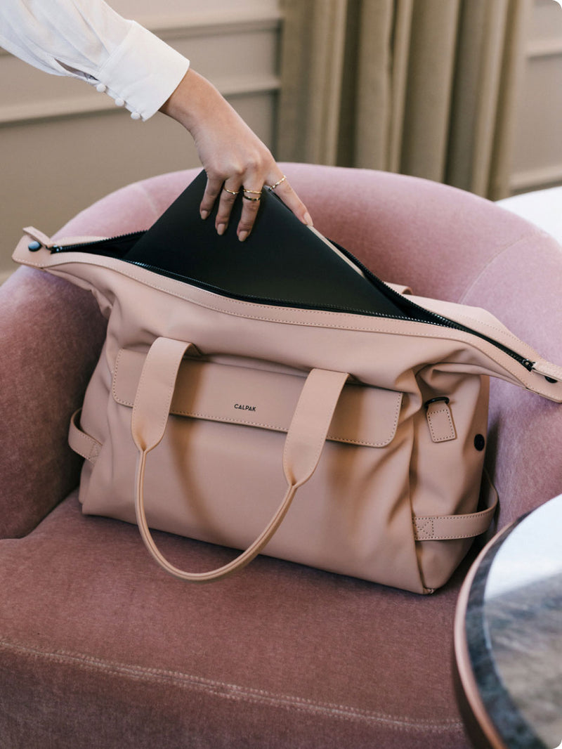 Model placing CALPAK bag on couch