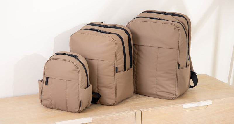 Luka Mini Backpack, Luka 15" Laptop Backpack and the Luka 17" Laptop Backpack in brown Chocolate on a table