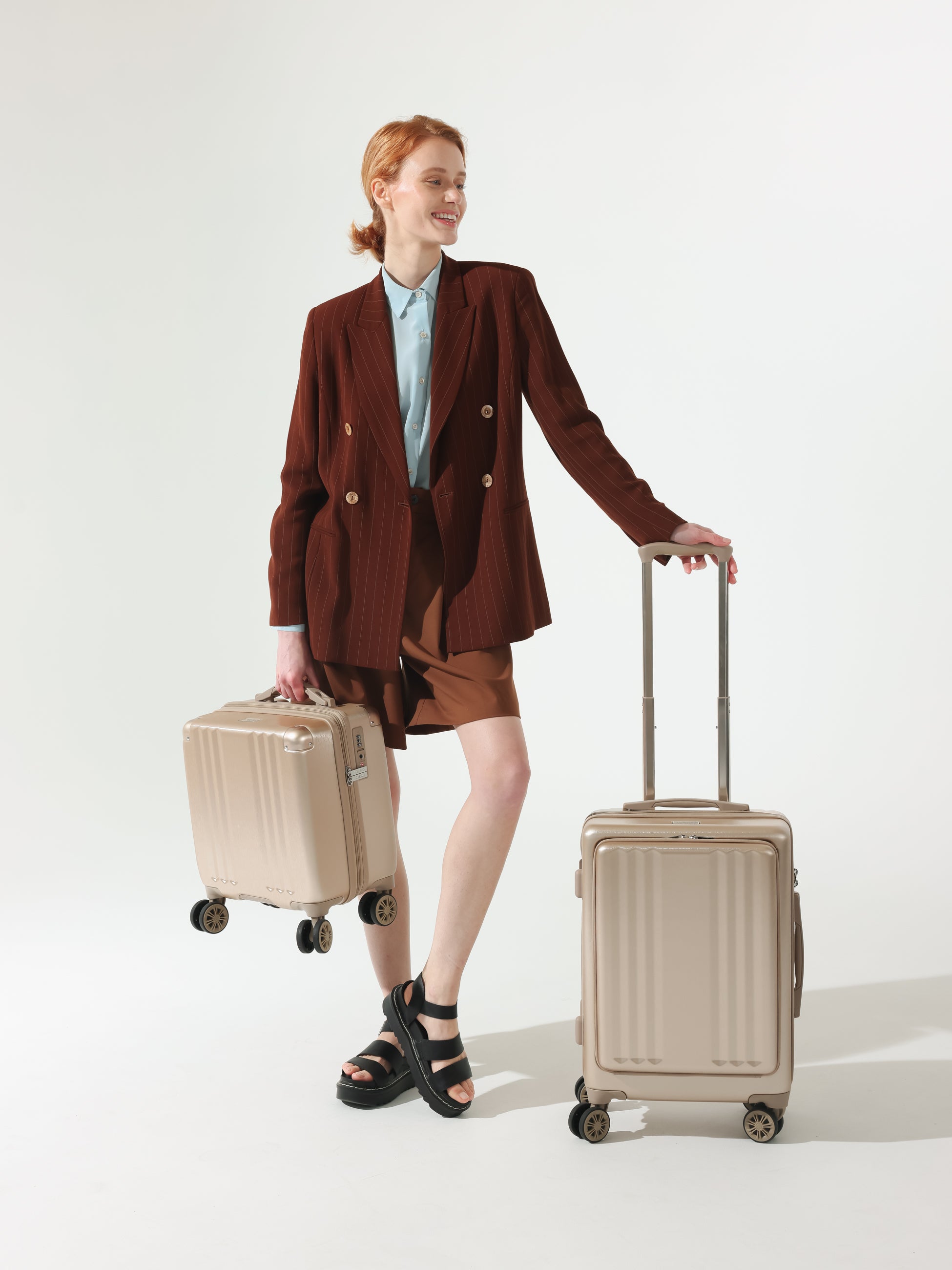 Model with CALPAK Ambeur hard shell carry-on with front pocket, cushioned top and side handles in gold