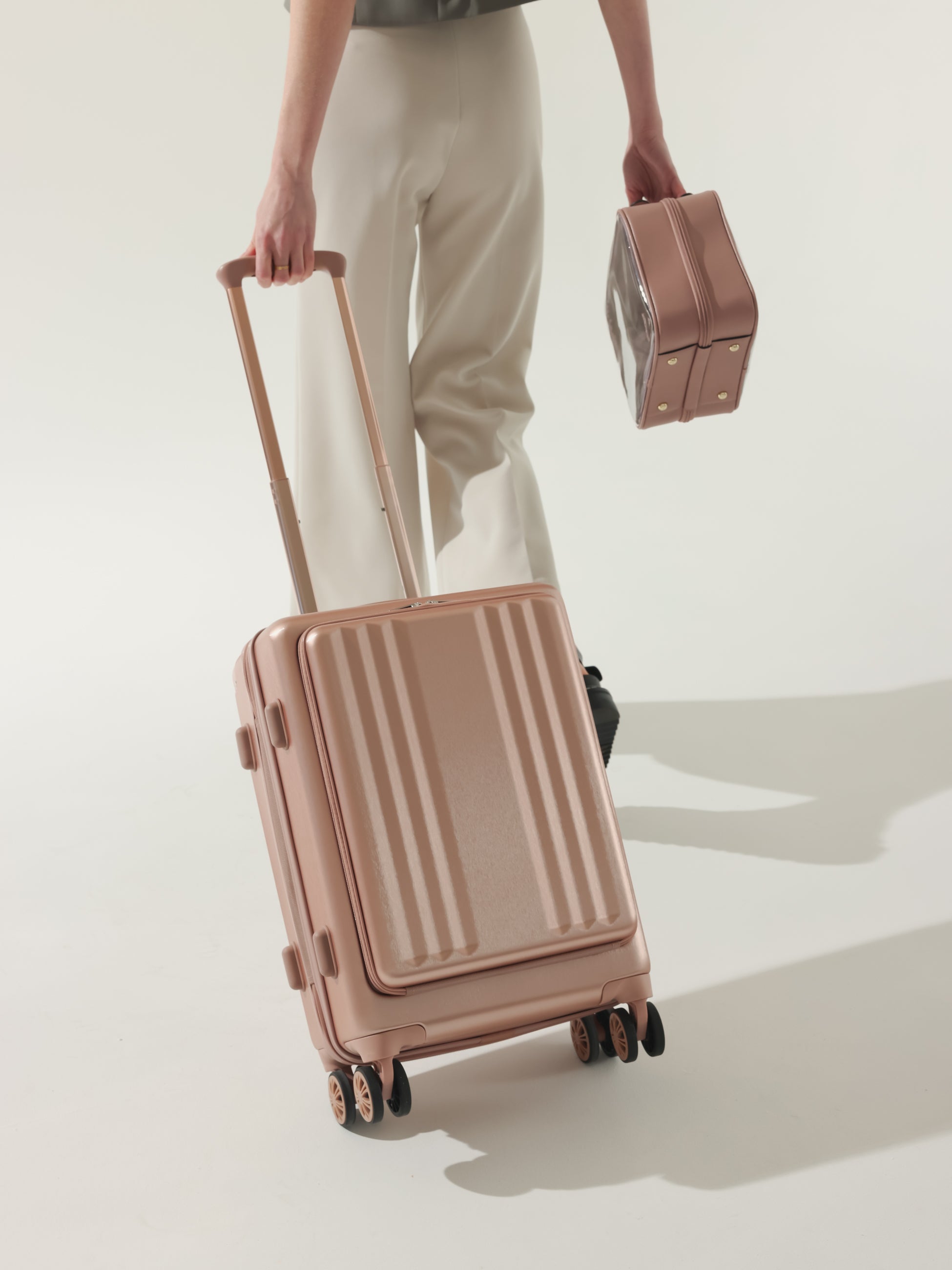 Model rolling CALPAK Ambeur carry on luggage with front pocket for laptop in rose gold