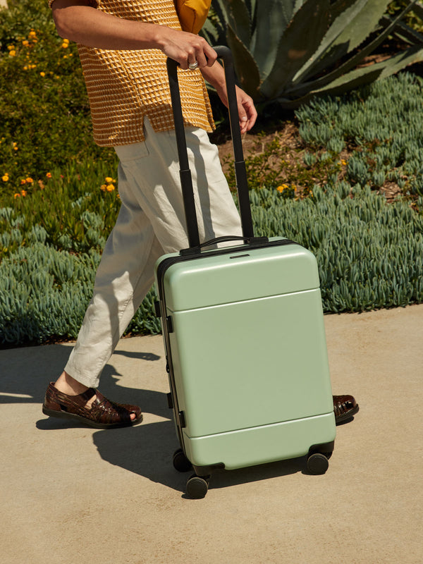 CALPAK Hue rolling carry-on suitcase in light green jade