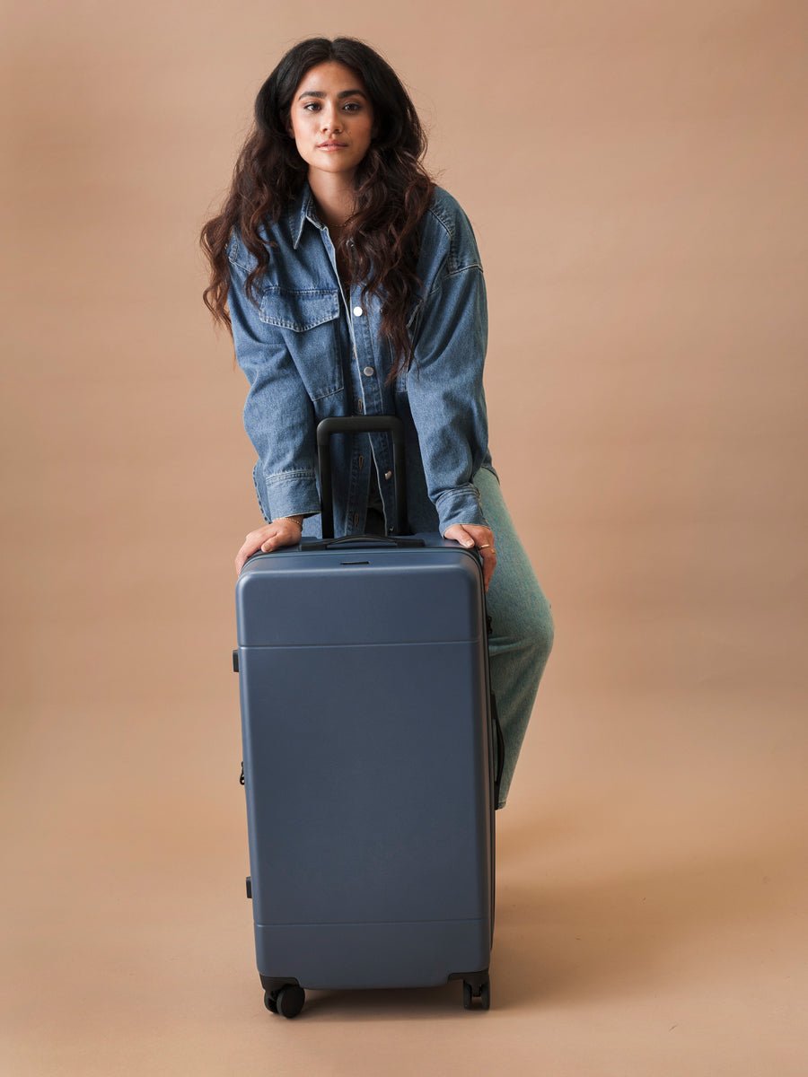 model with Hue Trunk luggage in atlantic blue