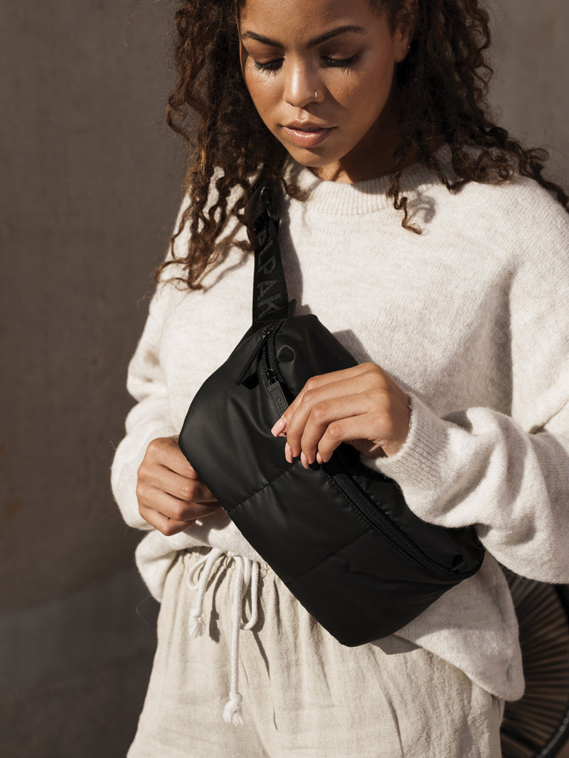 The Luka Belt Bag in black worn crossbody style. Featuring a zippered closure and a lightweight design.