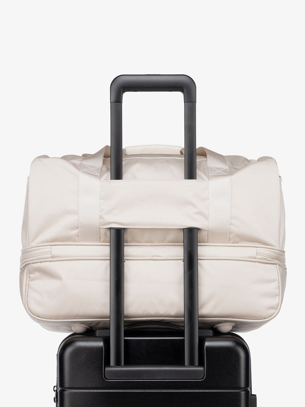 cream dune CALPAK Stevyn duffel bag with luggage trolley sleeve