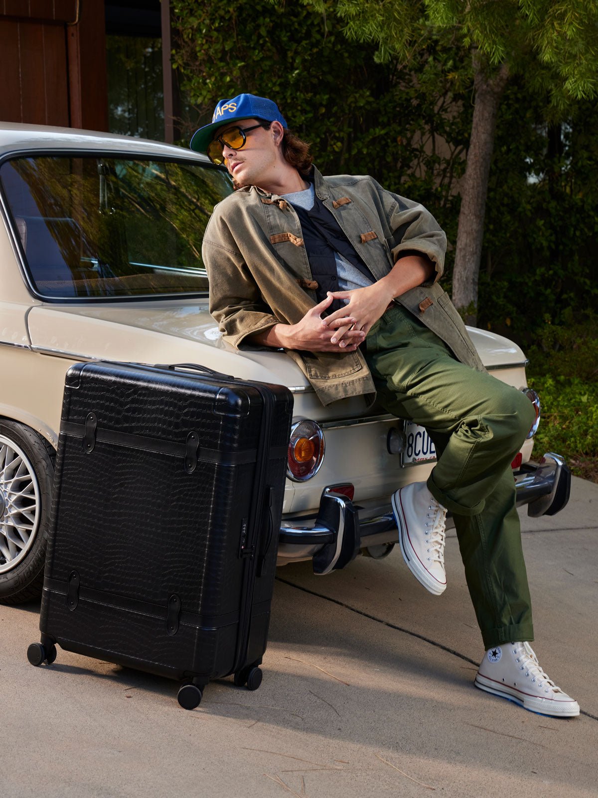 male model with CALPAK TRNK black luggage set in vintage trunk style