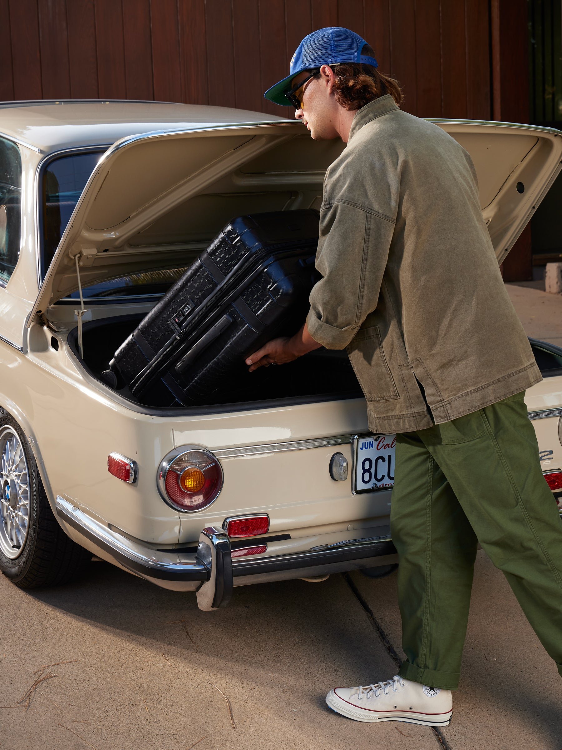 male model with CALPAK TRNK beige almond luggage set in vintage trunk style