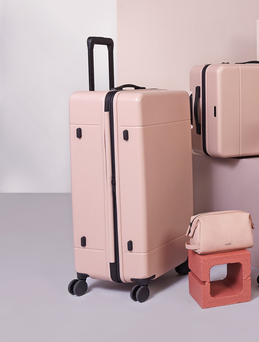 CALPAK Hue trunk suitcase in pink sand color with other pieces of CALPAK Hue collection