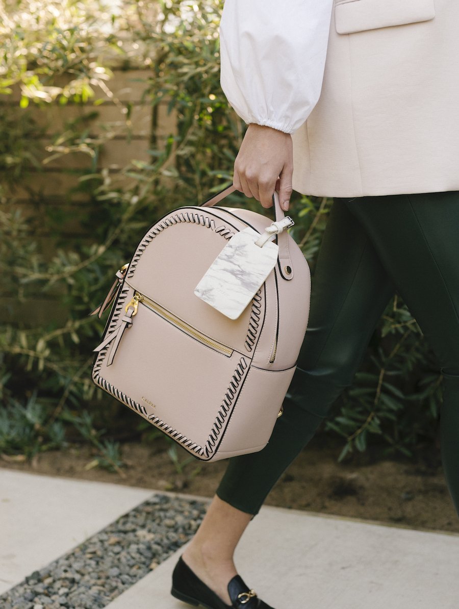Pink blush CALPAK Kaya backpack with power luggage tag