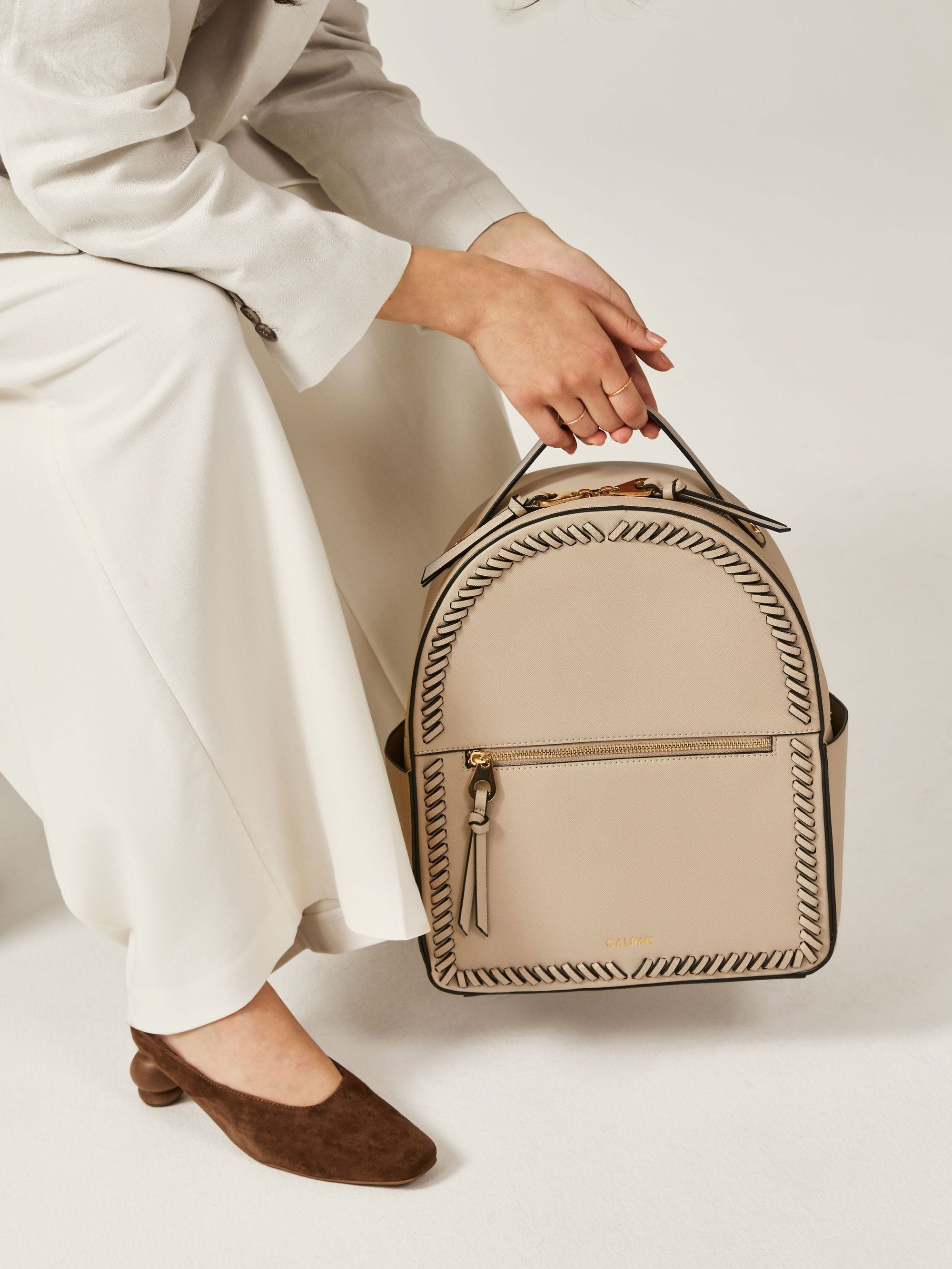 model holding beige stone CALPAK Kaya backpack