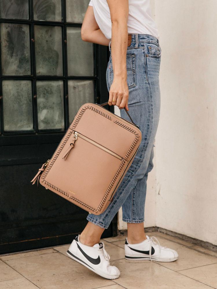 female model with a caramel brown CALPAK Kaya laptop backpack