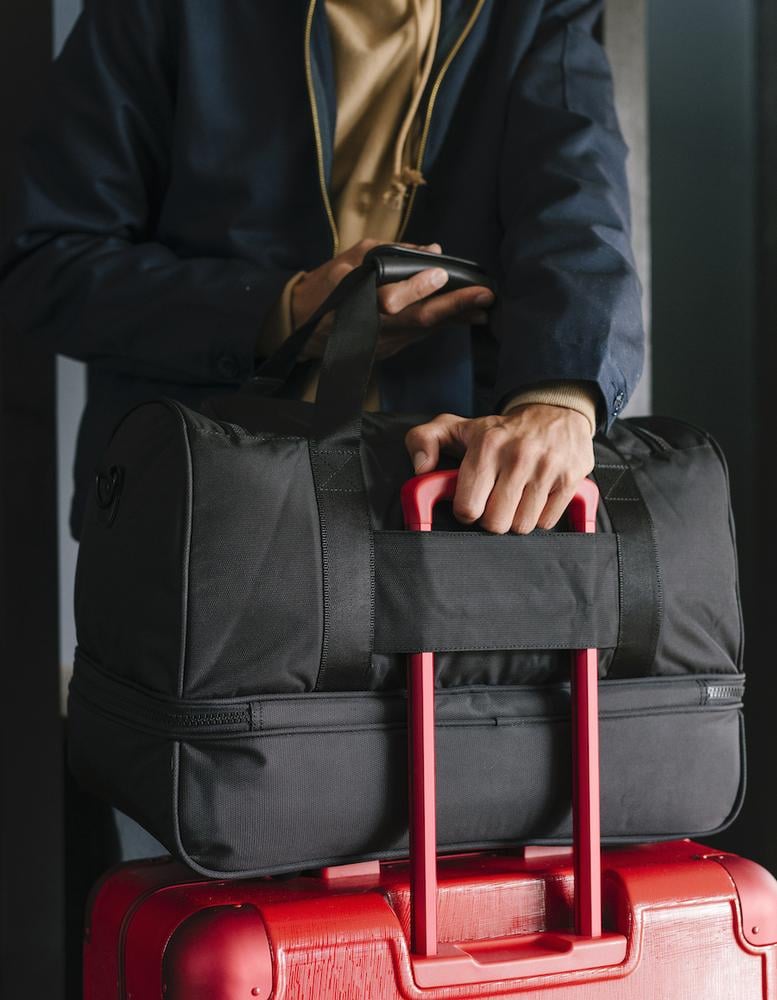 black CALPAK Stevyn duffel bag on a suitcase