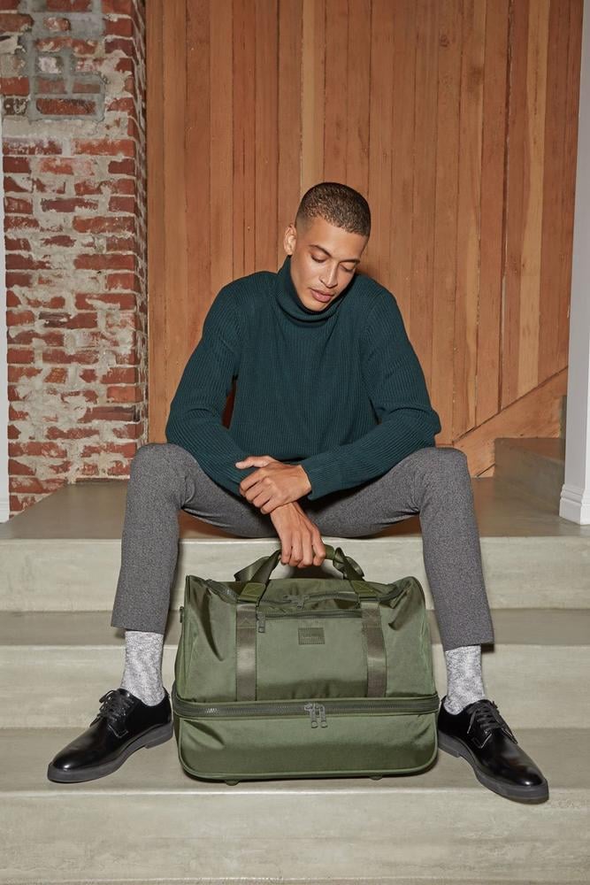 male model with green moss CALPAK Stevyn duffel bag