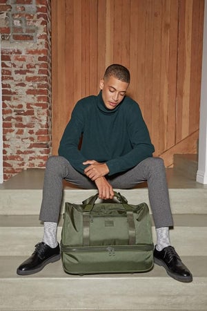 male model with green moss CALPAK Stevyn duffel bag; DST7019-MOSS